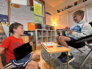 Two students smiling while playing a tabletop learning game in a classroom.