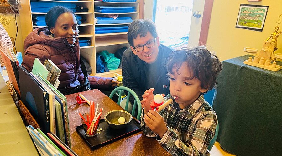 Child demonstrating a hands-on activity while family members watch in a classroom.