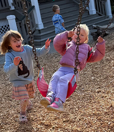 Children playing together on swings in an outdoor play area.
