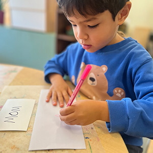 Young child writing with a pencil during a classroom activity.
